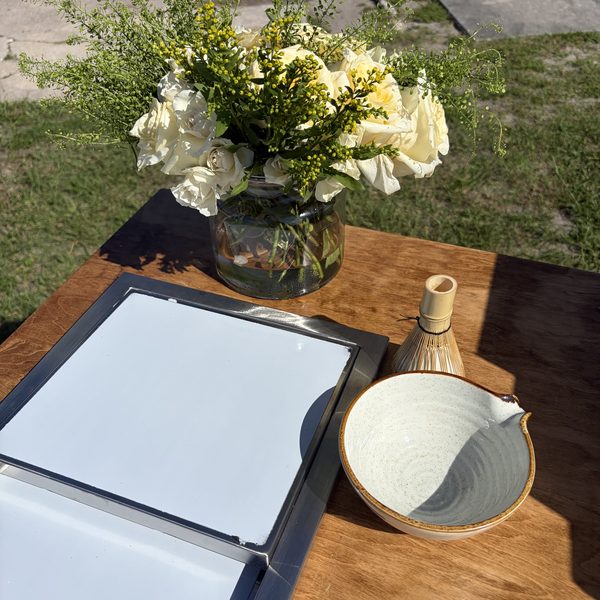 Menu board, matcha whisk and flowers on the counter